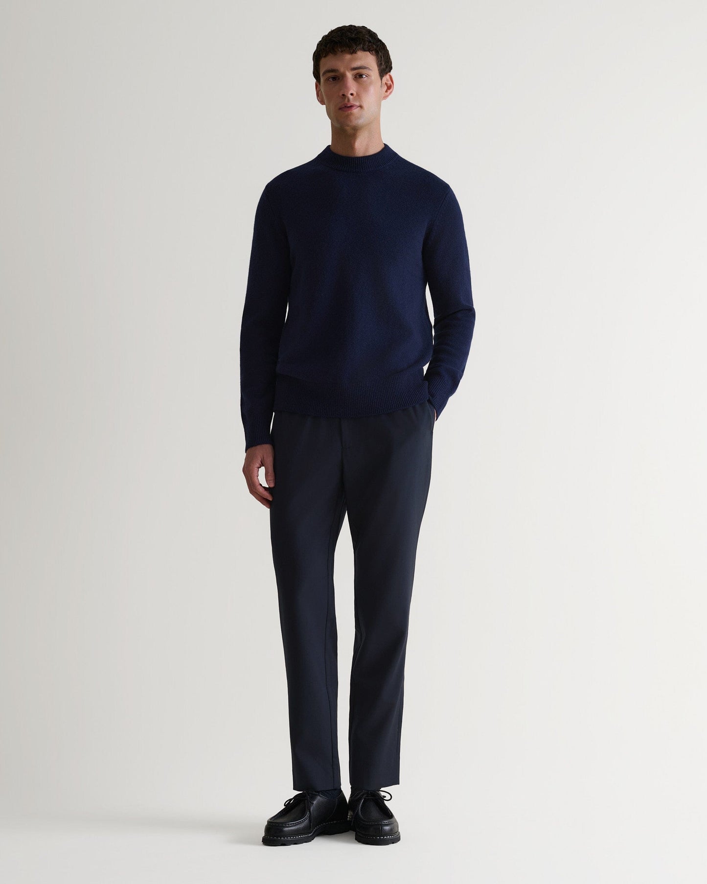 Image 1 of 4 showing man wearing Rise & Fall's Finest Cashmere Mid-Weight Crew Neck Jumper in navy with tailored black trousers.