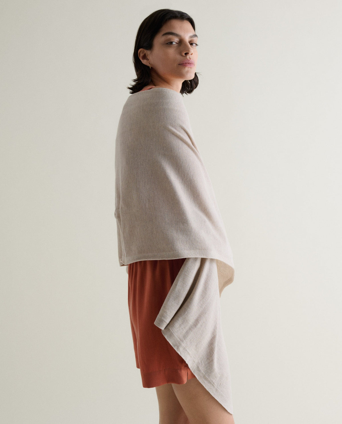 Image 1 of 6 showing woman wrapping Rise & Fall's oversized cashmere scarf around shoulders, colour: light beige.