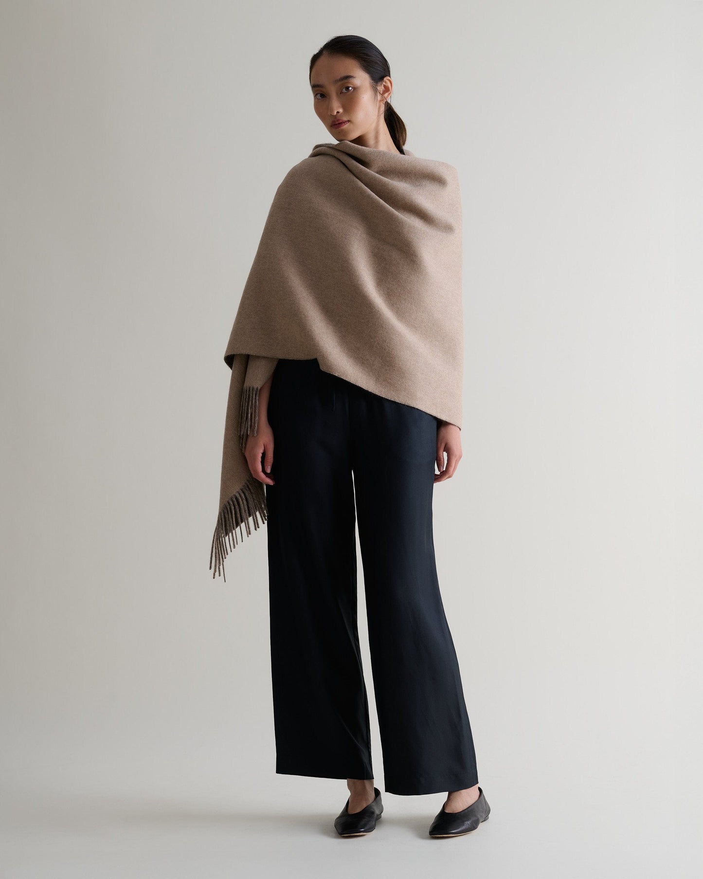 Image 1 of 7 showing woman wearing Rise & Fall's finest cashmere double faced wrap twine side with black trousers.