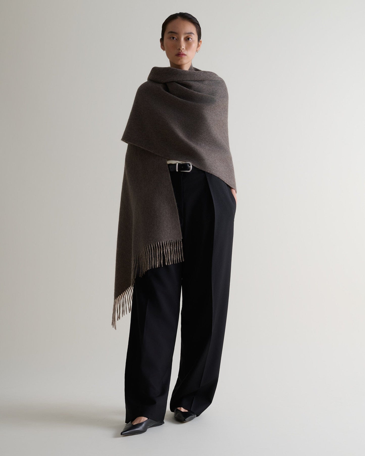 Image 2 of 7 showing woman wearing Rise & Fall's finest cashmere double faced wrap mole side with black trousers.