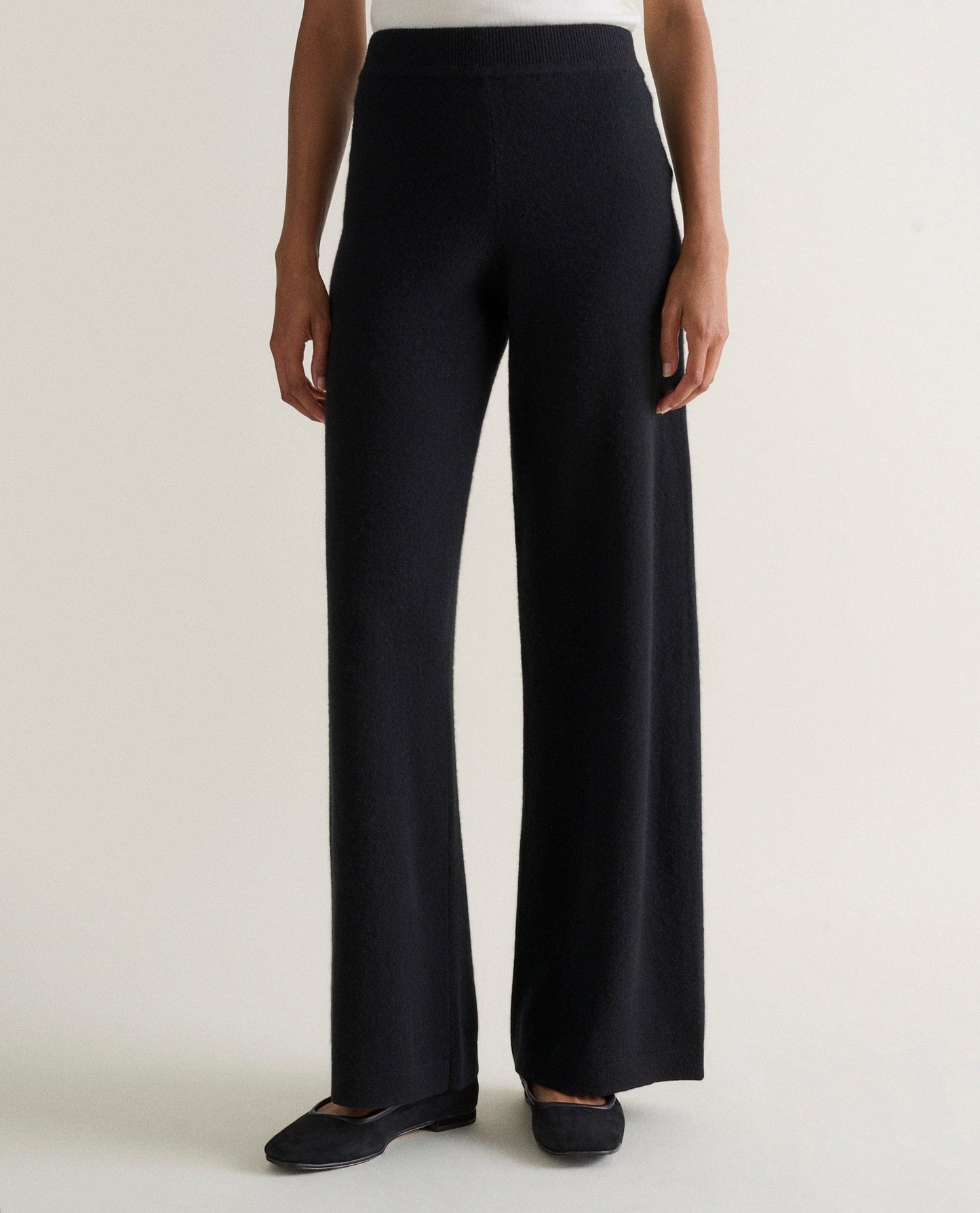 Image 3 of 4 showing woman wearing Rise & Fall's black fine cashmere wide-leg trousers with a white top.