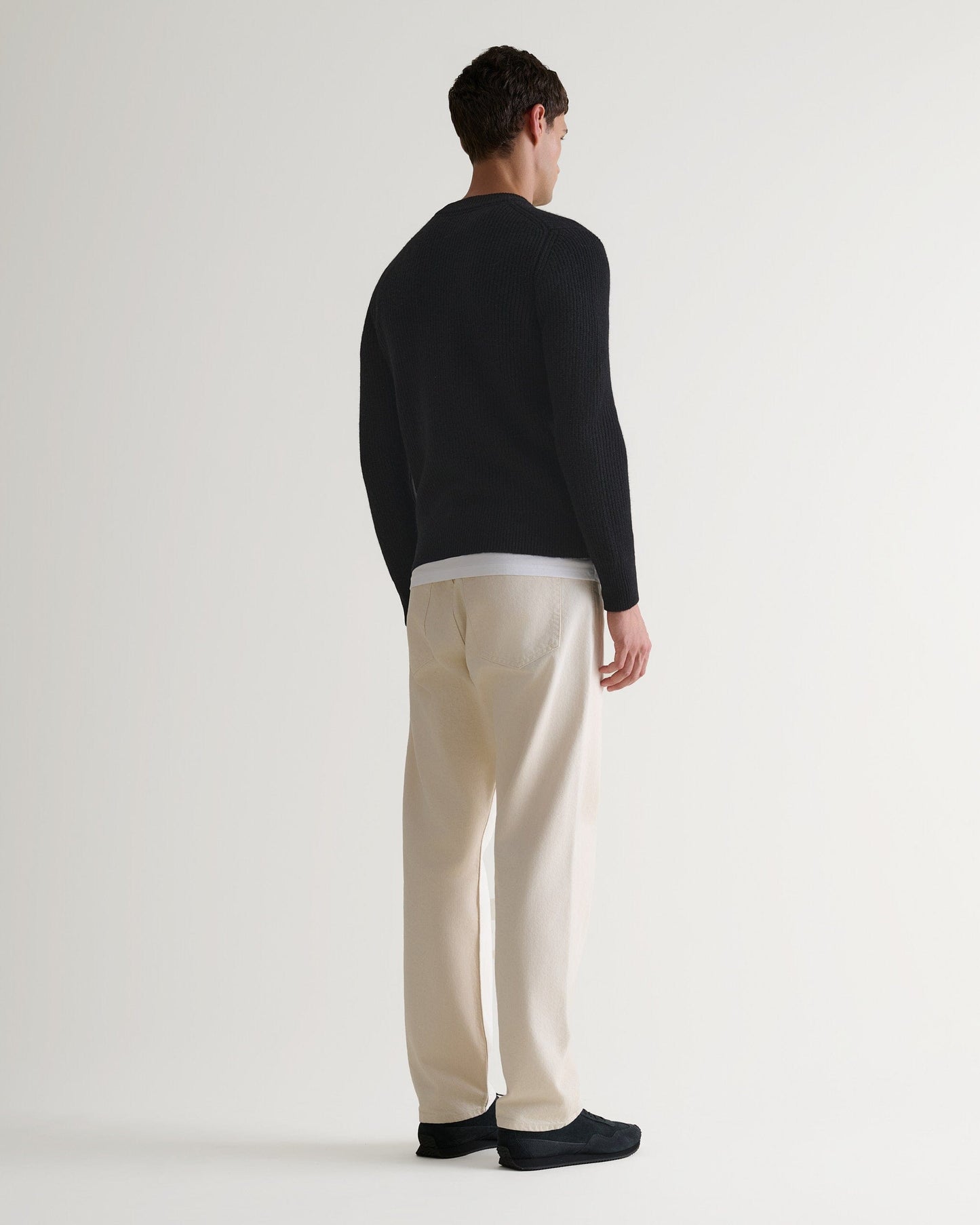 Image 3 of 5 showing back of man wearing Rise & Fall's Cashmere Merino Fishermans Rib Crew Neck Jumper in black.