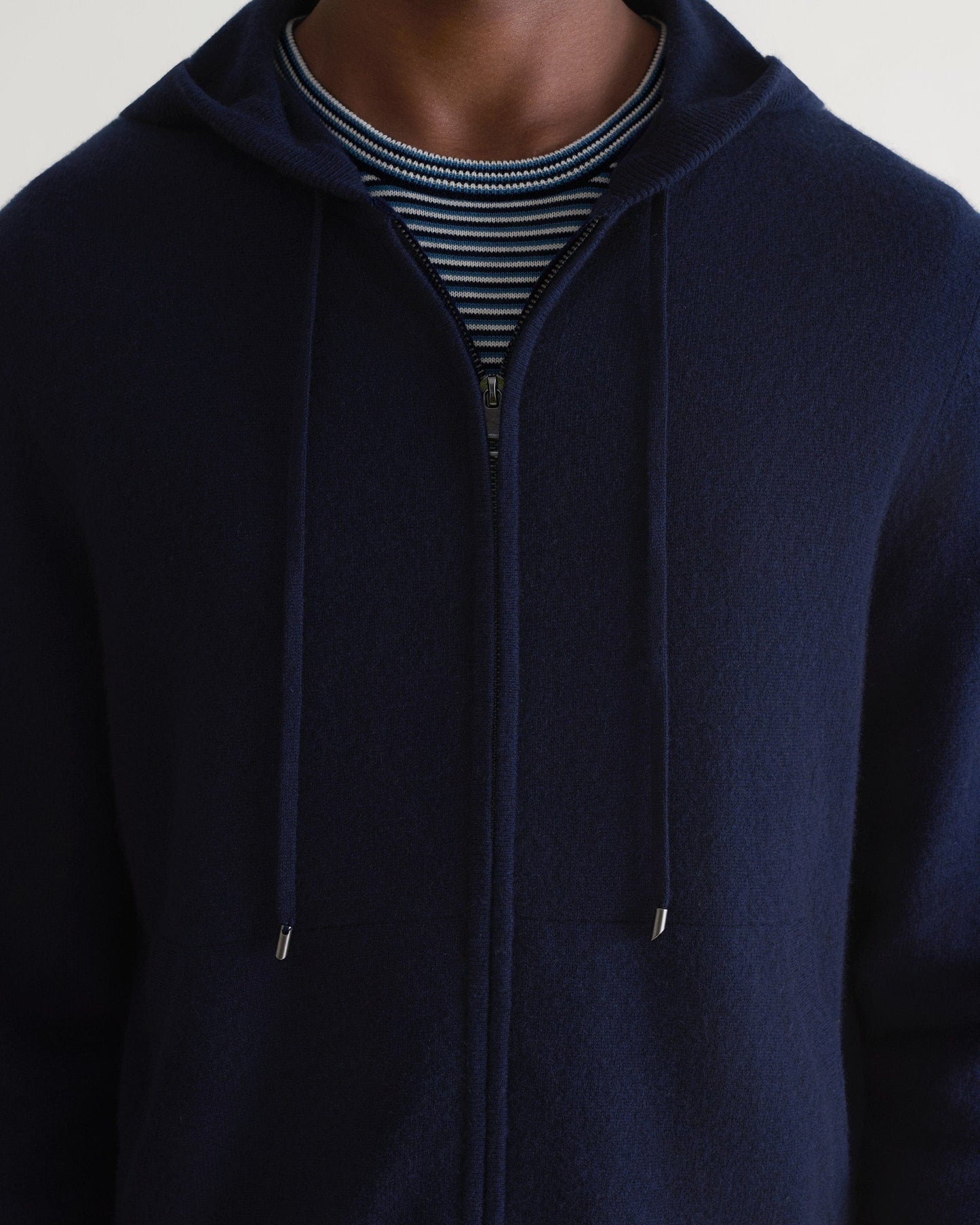 Image 3 of 5 showing man wearing Rise & Fall's fine cashmere zip hoodie, navy, close up.