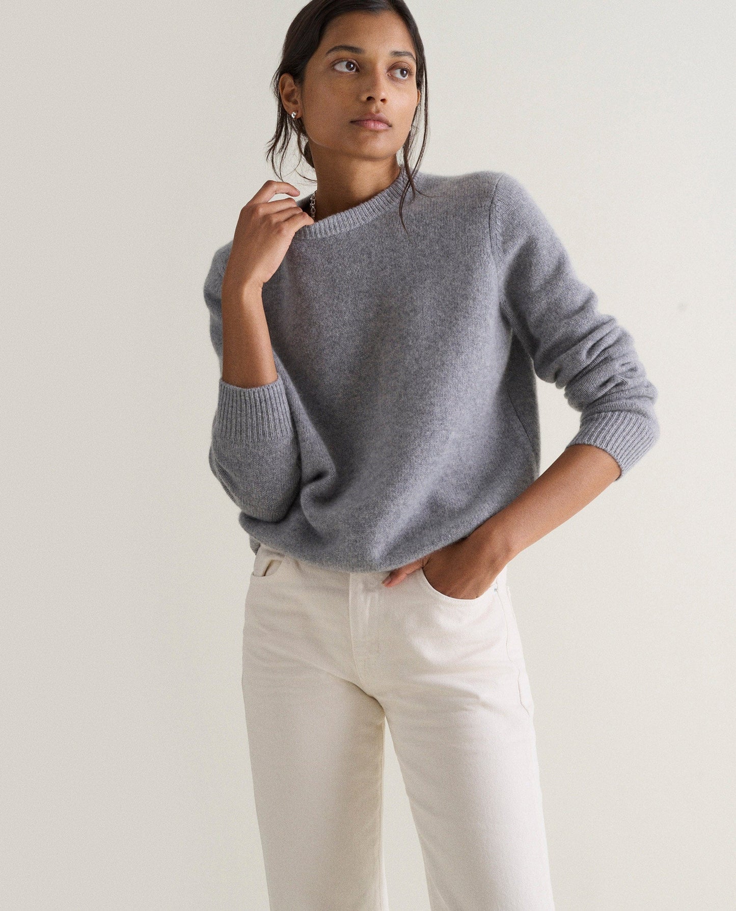 Image 3 of 5 showing woman wearing Rise & Fall's grey mid-weight cashmere crew neck jumper with white jeans.