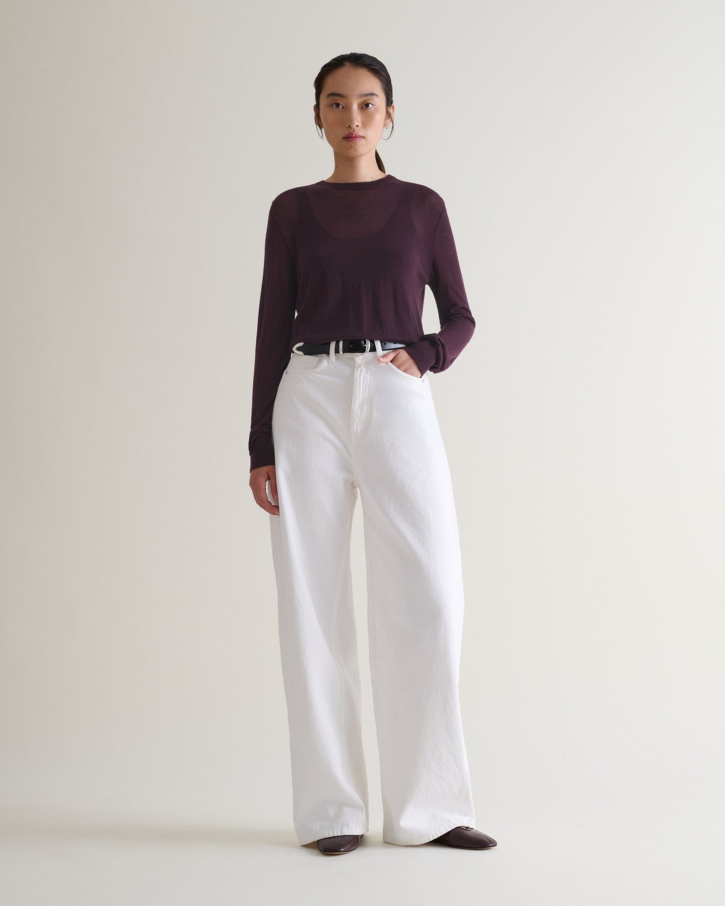 Image 3 of 5 showing a woman wearing Rise & Fall's oxblood tencel™ cashmere double layered crew neck jumper with white jeans and black leather belt.