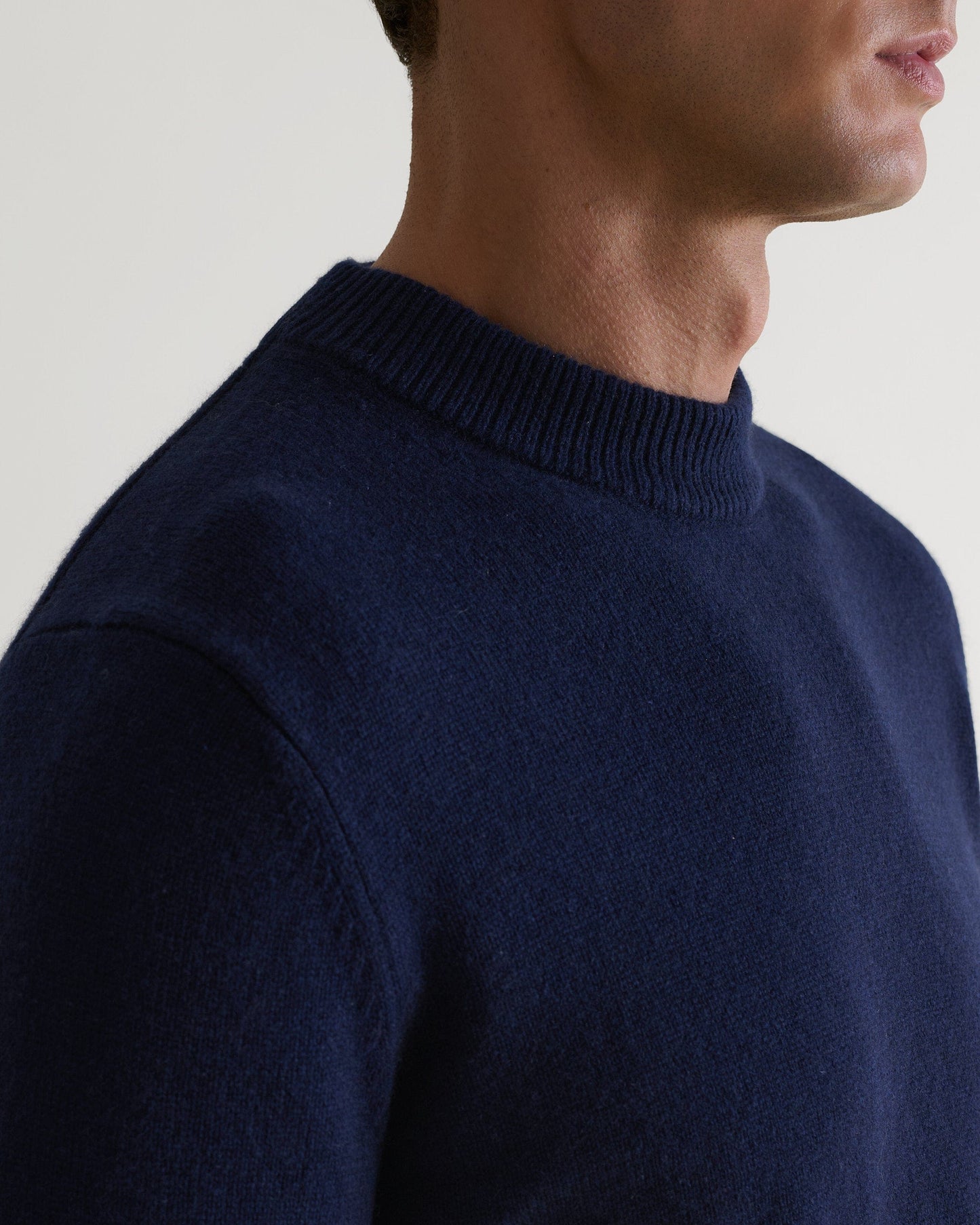 Image 4 of 4 showing close up of man wearing Rise & Fall's Finest Cashmere Mid-Weight Crew Neck Jumper in navy.