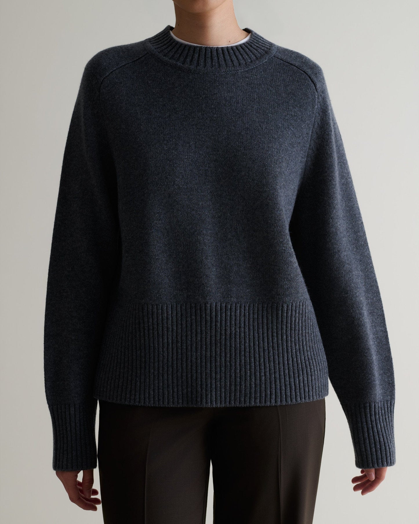 Image 4 of 5 showing woman wearing Rise & Fall cashmere merino saddle sleeve crew neck jumper, colour: graphite.
