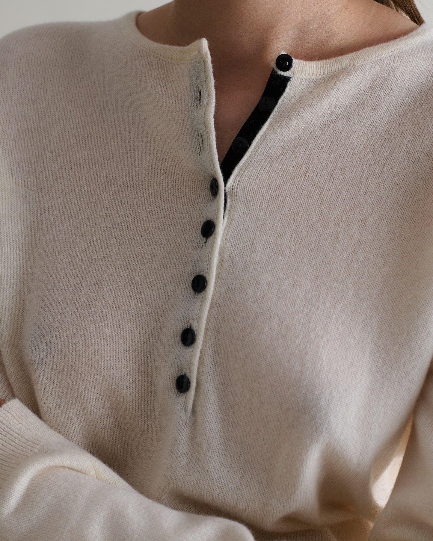 Image 4 of 5 showing a close up of a woman wearing Rise & Fall's buttermilk cashmere merino henley jumper.