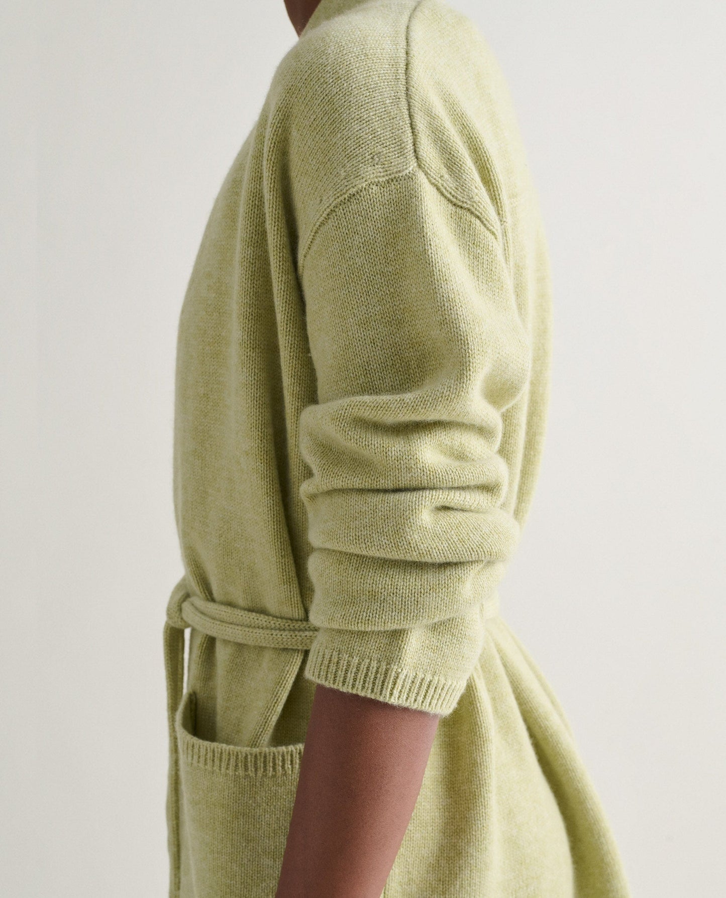 Image 5 of 5 showing side view of woman wearing Rise & Fall's lichen green cashmere merino belted cardigan.