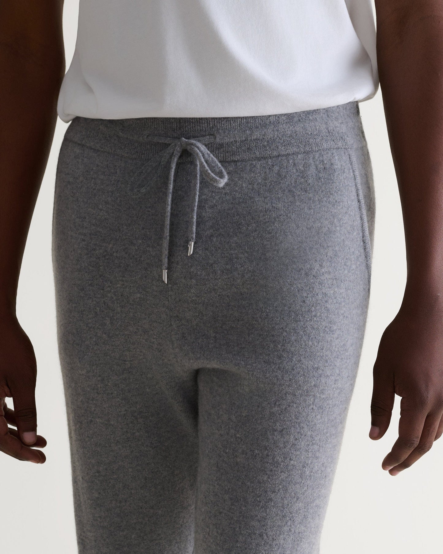 Image 5 of 6 showing man wearing Rise & Fall's fine cashmere joggers, grey, close up.