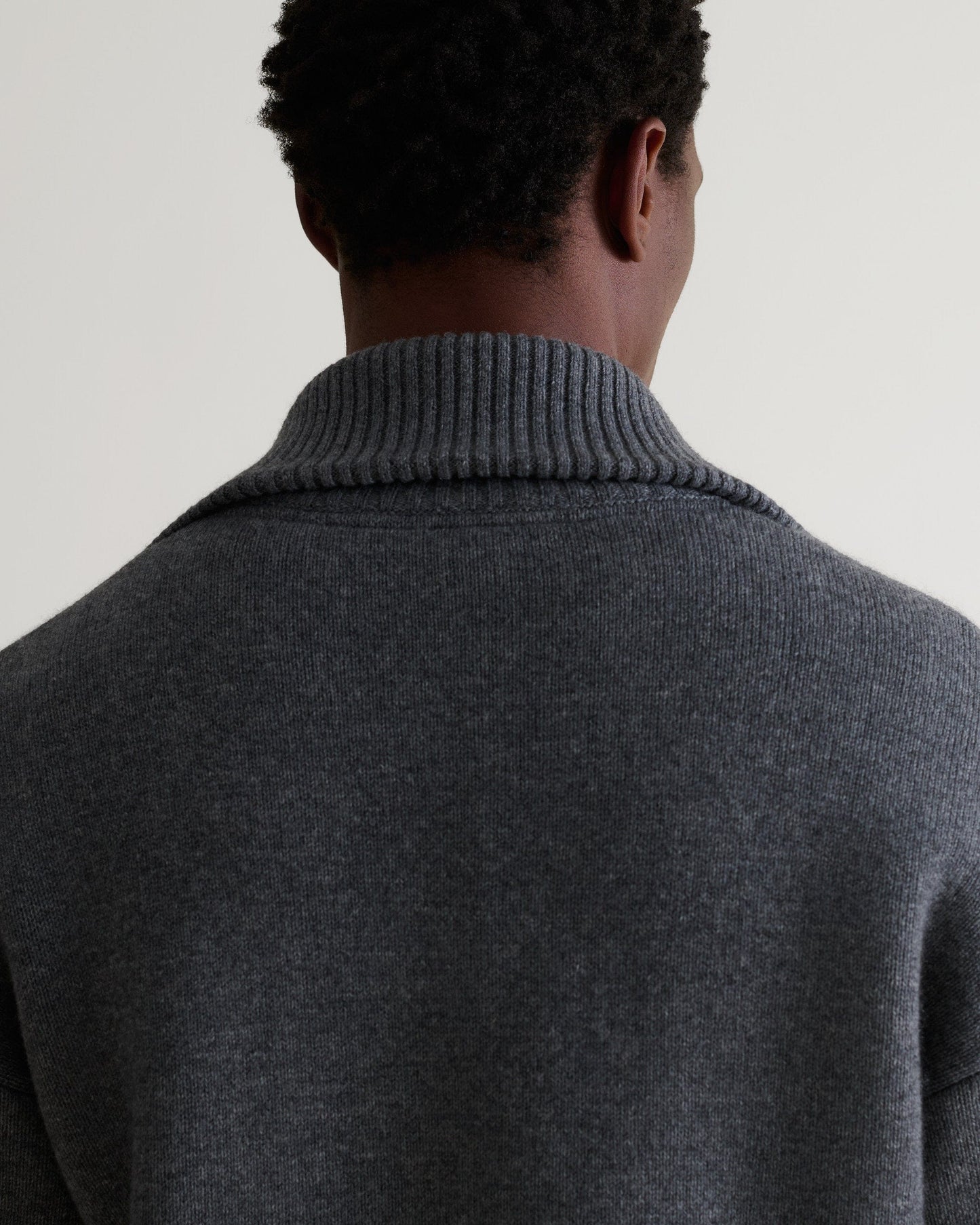 Image 6 of 6 showing man wearing Rise & Fall's dark grey cashmere merino buttoned knitted bomber. Close up of shoulder and back.