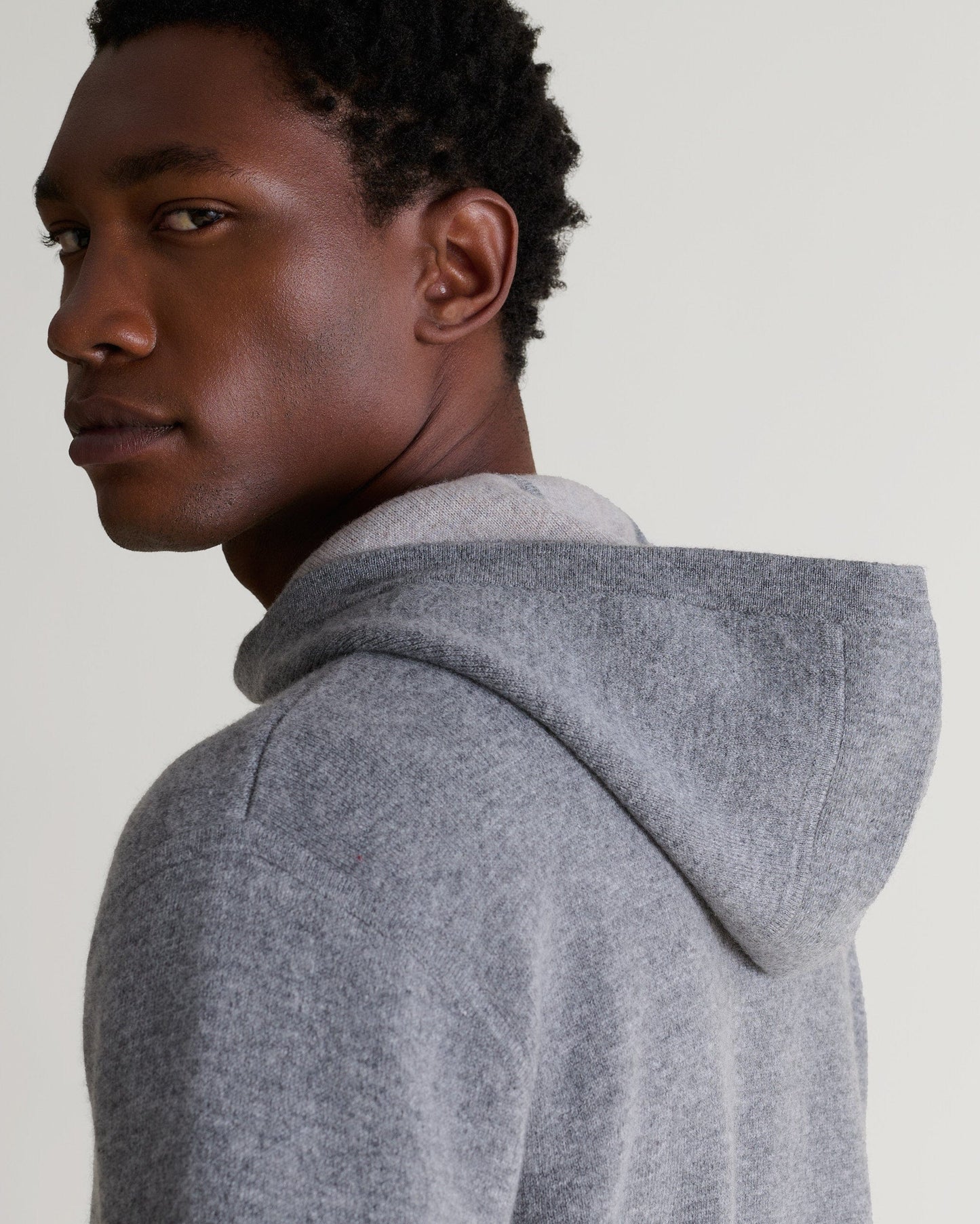 Close up side view of man wearing Rise & Fall's grey cashmere merino double-faced hoodie.