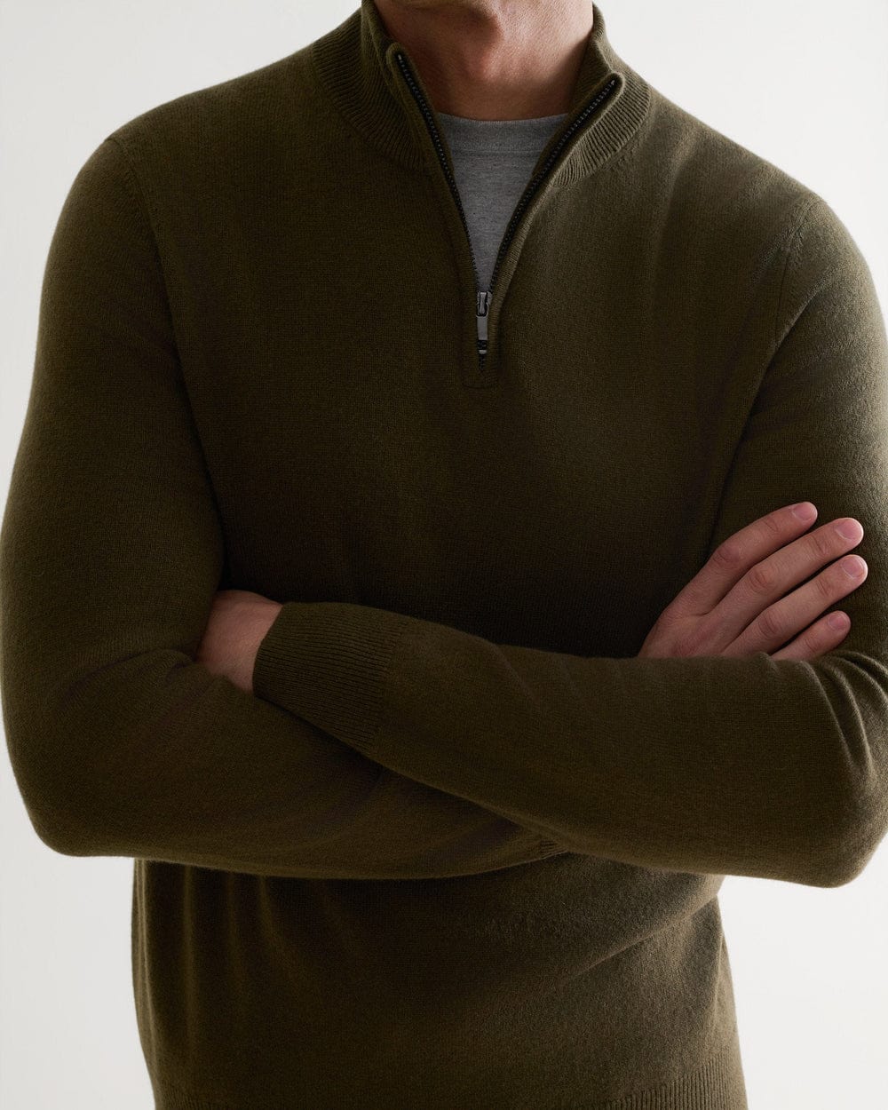 Close up of man wearing Rise & Fall's military green finest cashmere 1/4 zip jumper with a grey T-shirt.