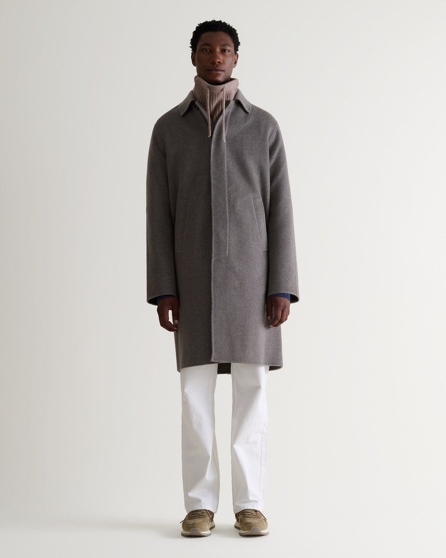 Full portrait view of man wearing toast cashmere merino drawstring snood with grey wool overcoat