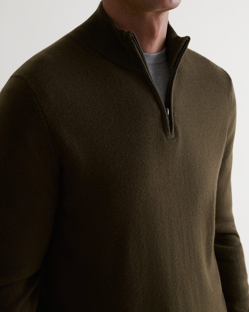 Close up side view of man wearing Rise & Fall's military green finest cashmere 1/4 zip jumper. Worn with grey T-shirt.