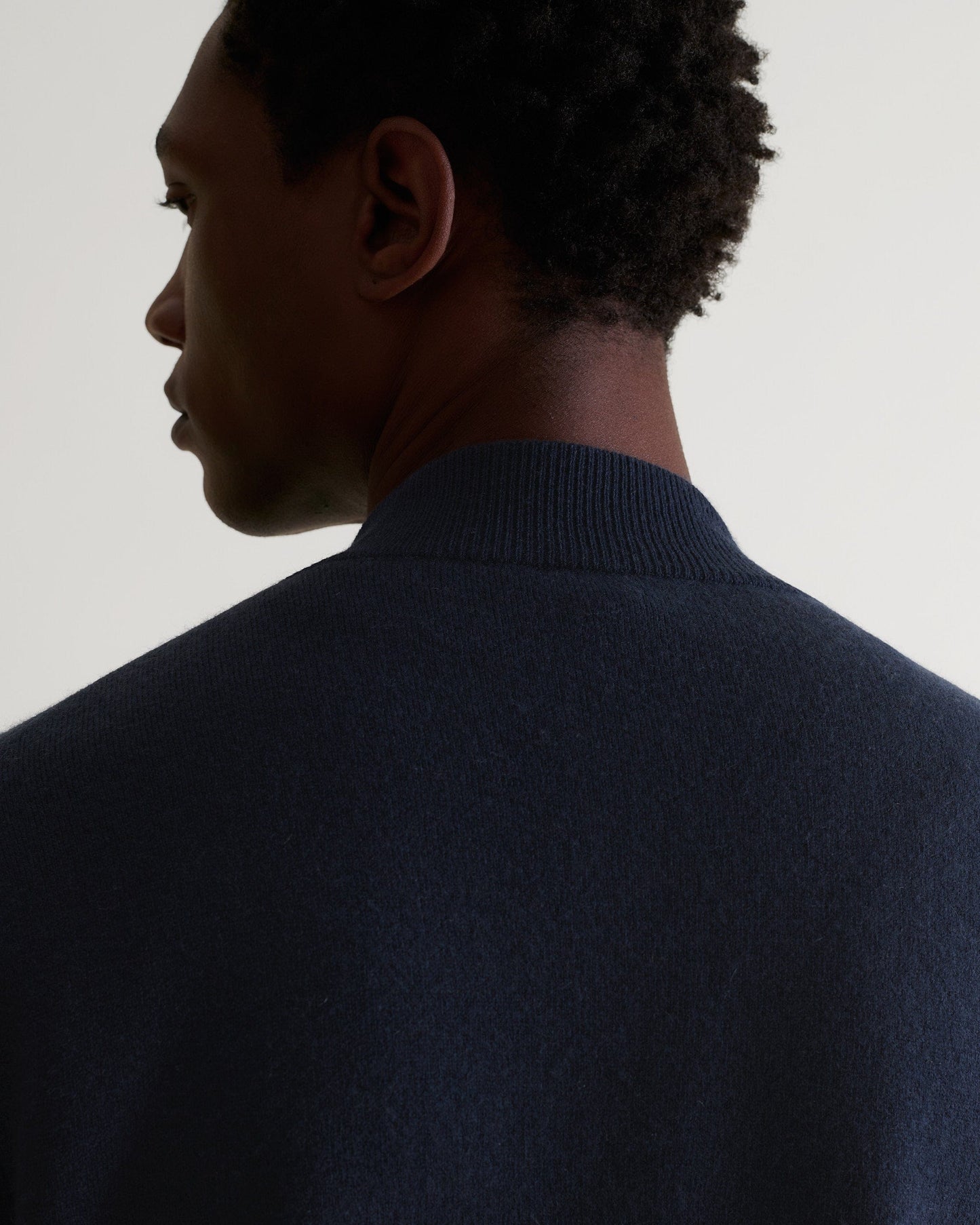 Back of man wearing Rise & Fall's navy cashmere merino double-faced knitted bomber jacket.