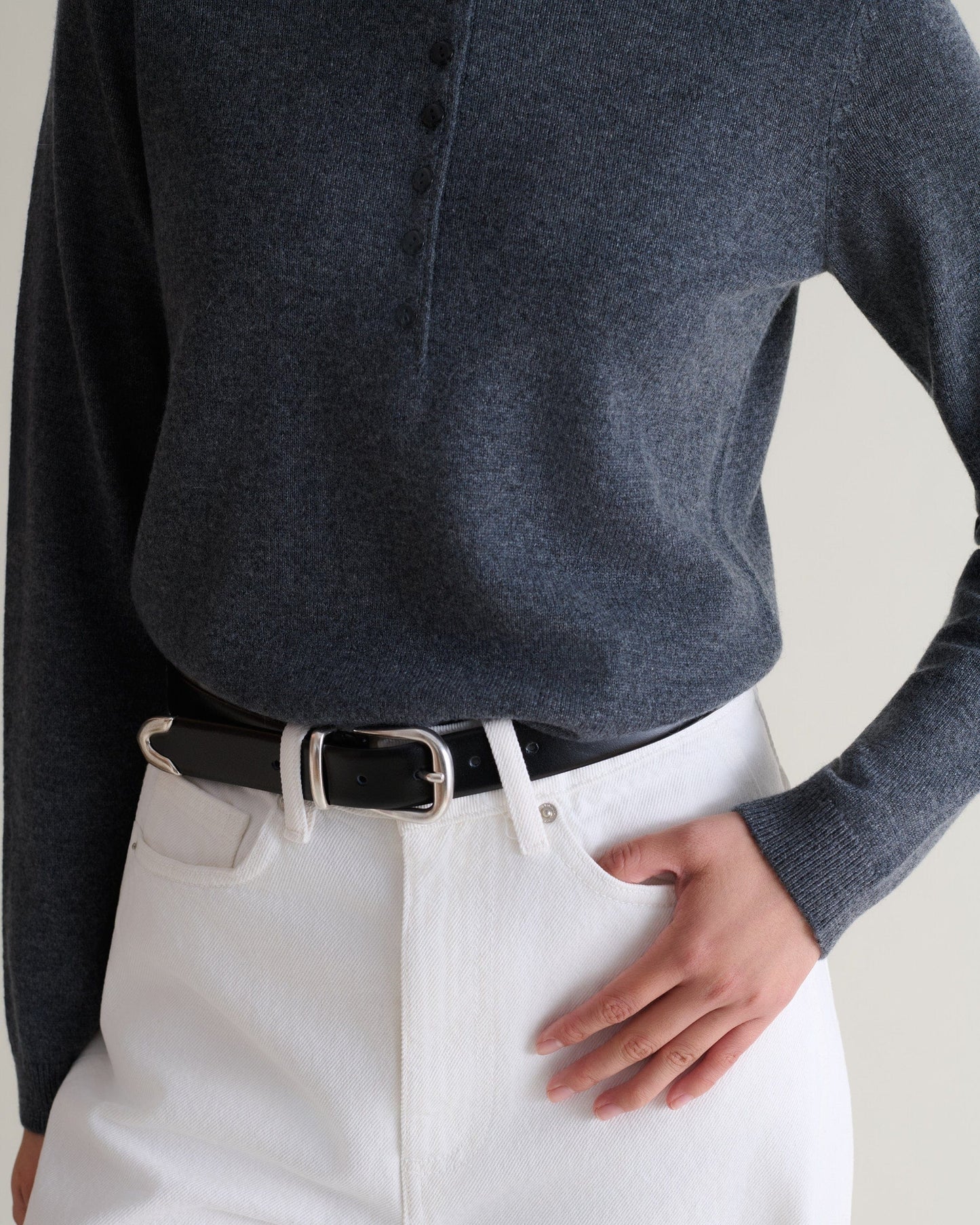 Close up of Rise & Fall's graphite cashmere merino henley jumper. Worn with wide jeans and a black leather belt.