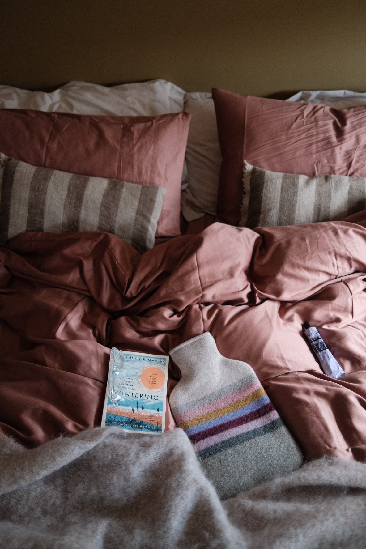 A lived-in bed with a book and a hot water bottle