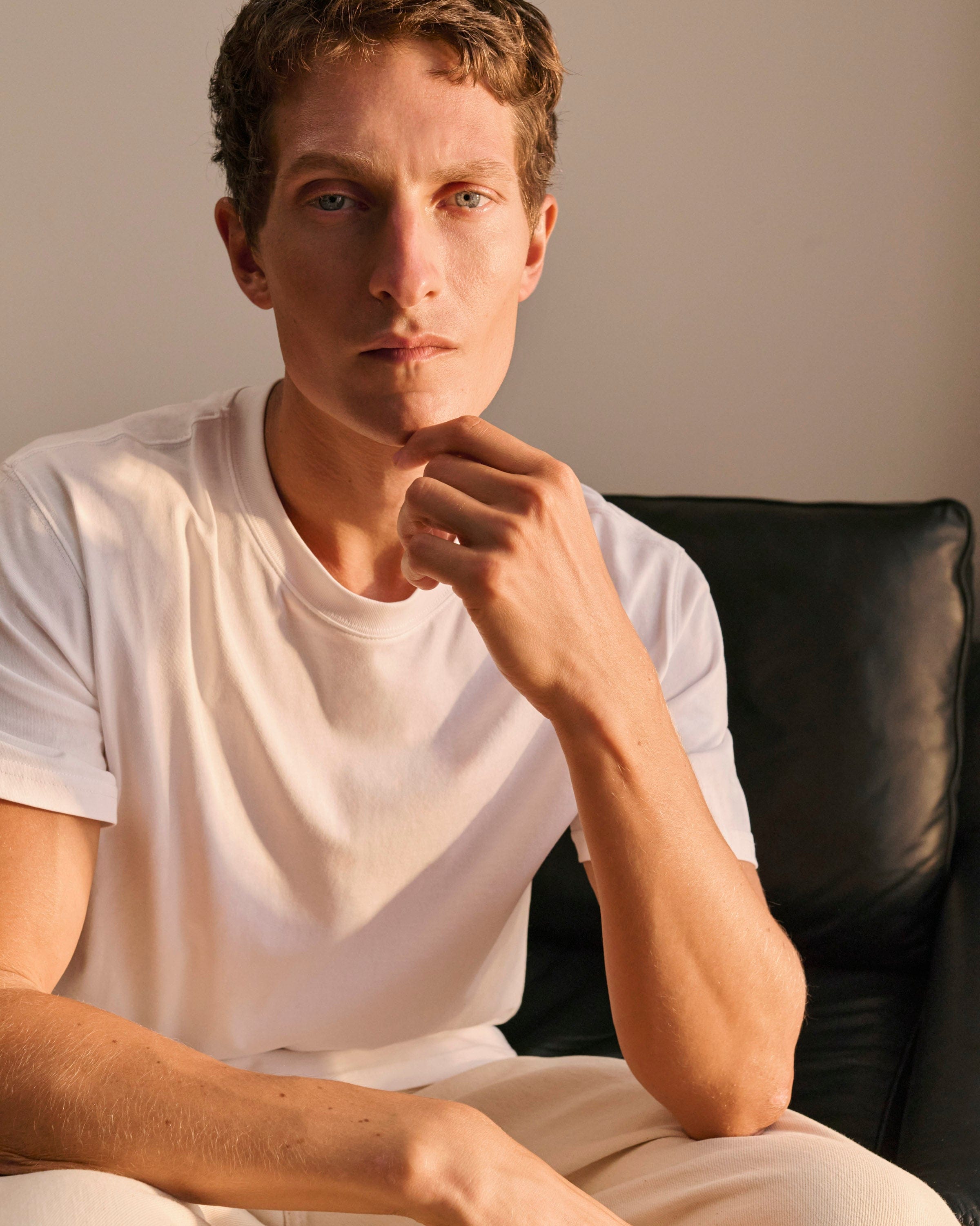 Man wears white crew neck -shirt and beige chinos.