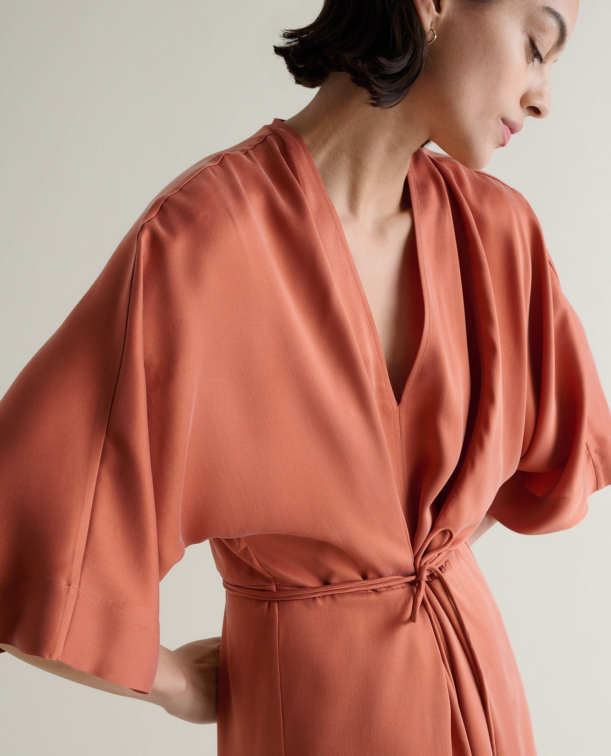 Woman weaing a rust coloured silk dress.