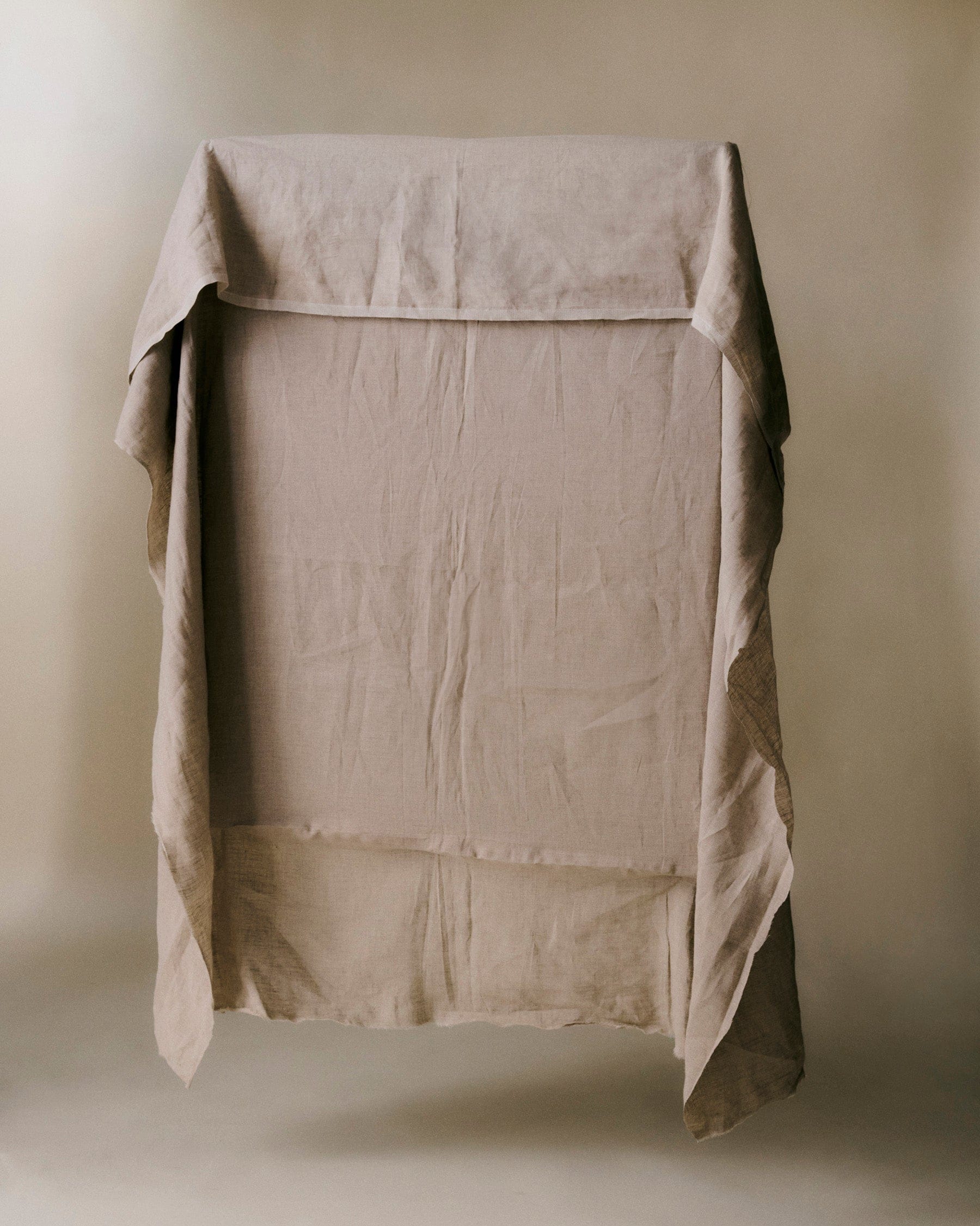 Beige linen sheet draping above the floor.