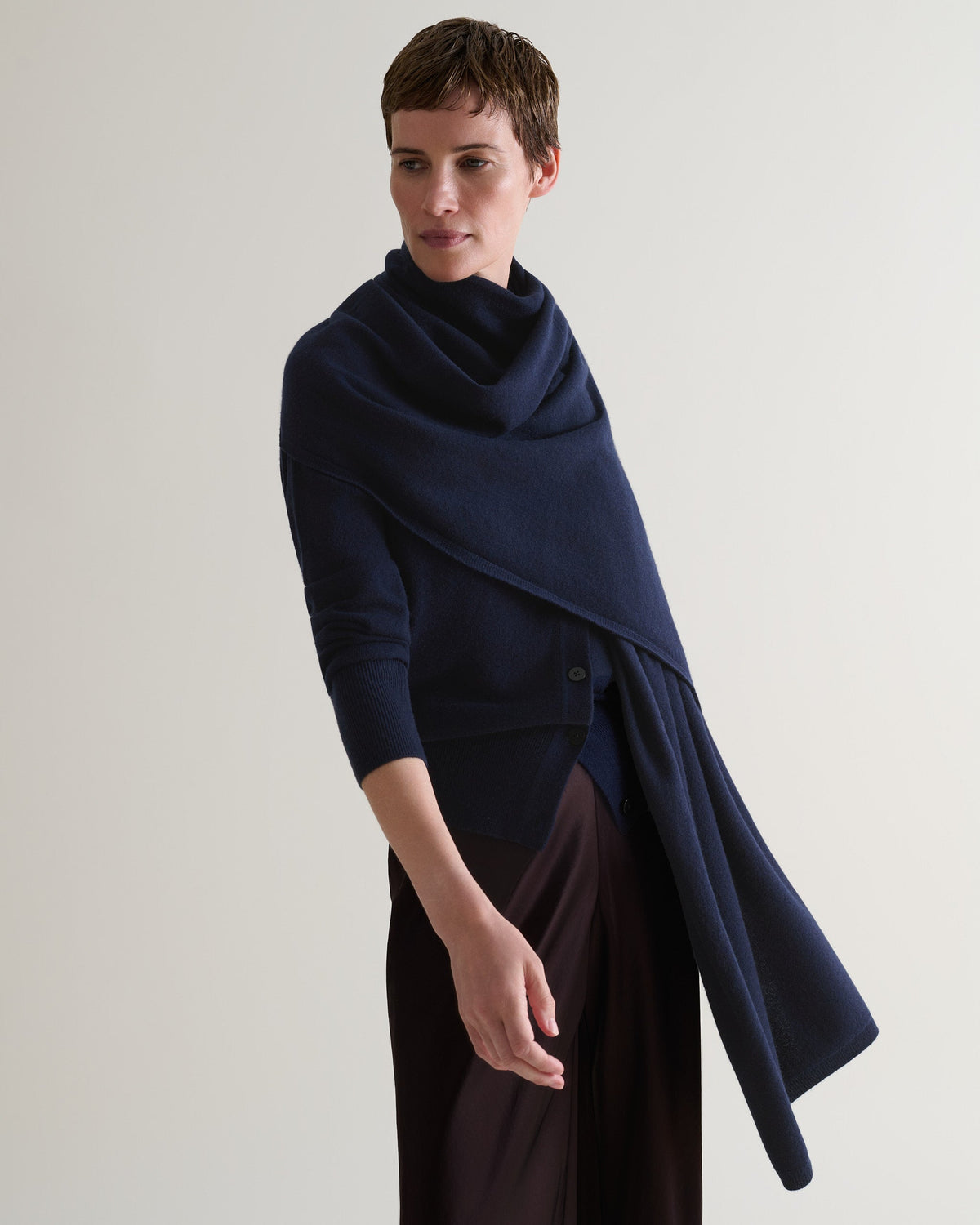 Women wears cashmere wrap over navy cardigan.