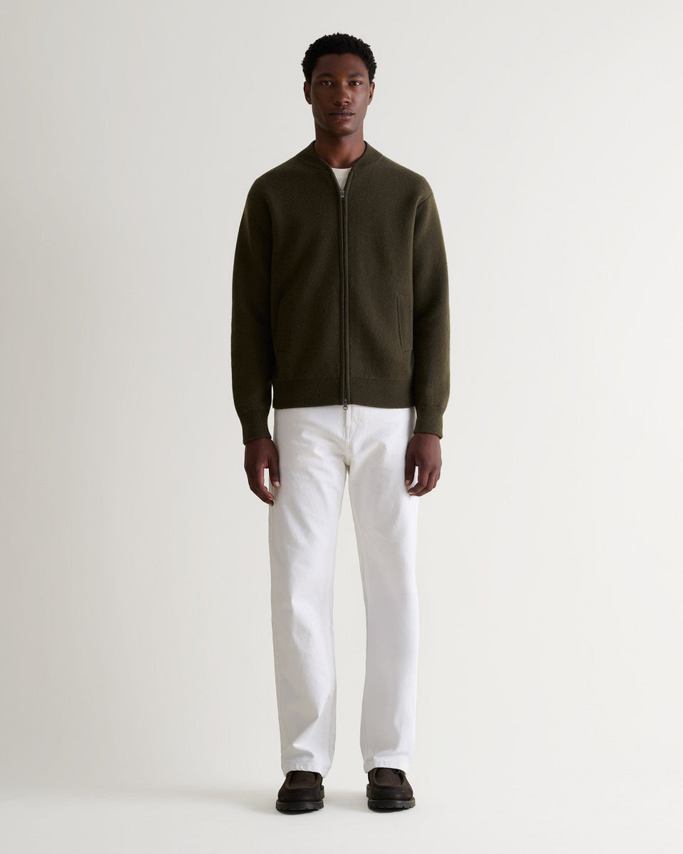 Full length of man wearing dark green cashmere merino double-faced knitted bomber jacket with white T-shirt and jeans.