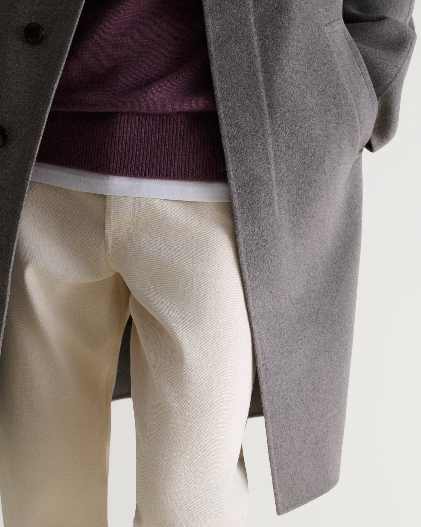 Fawn coloured cashmere merino double-faced wool coat. Matched with cream jeans and burgundy jumper. Lower half close up.