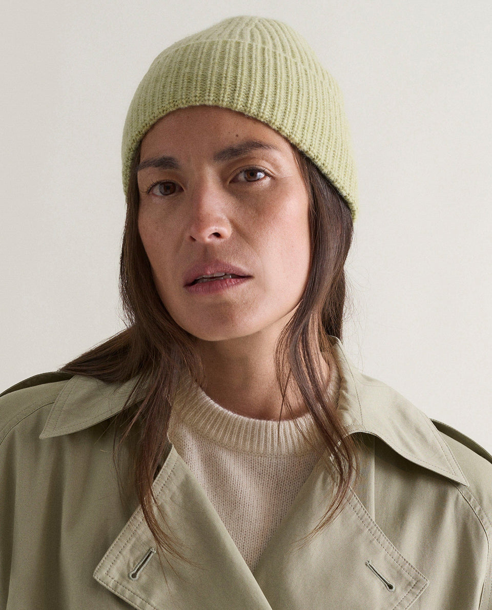 Image 1 of 2 showing woman wearing Rise & Fall's Cashmere Merino Ribbed Knit Beanie in lichen green.
