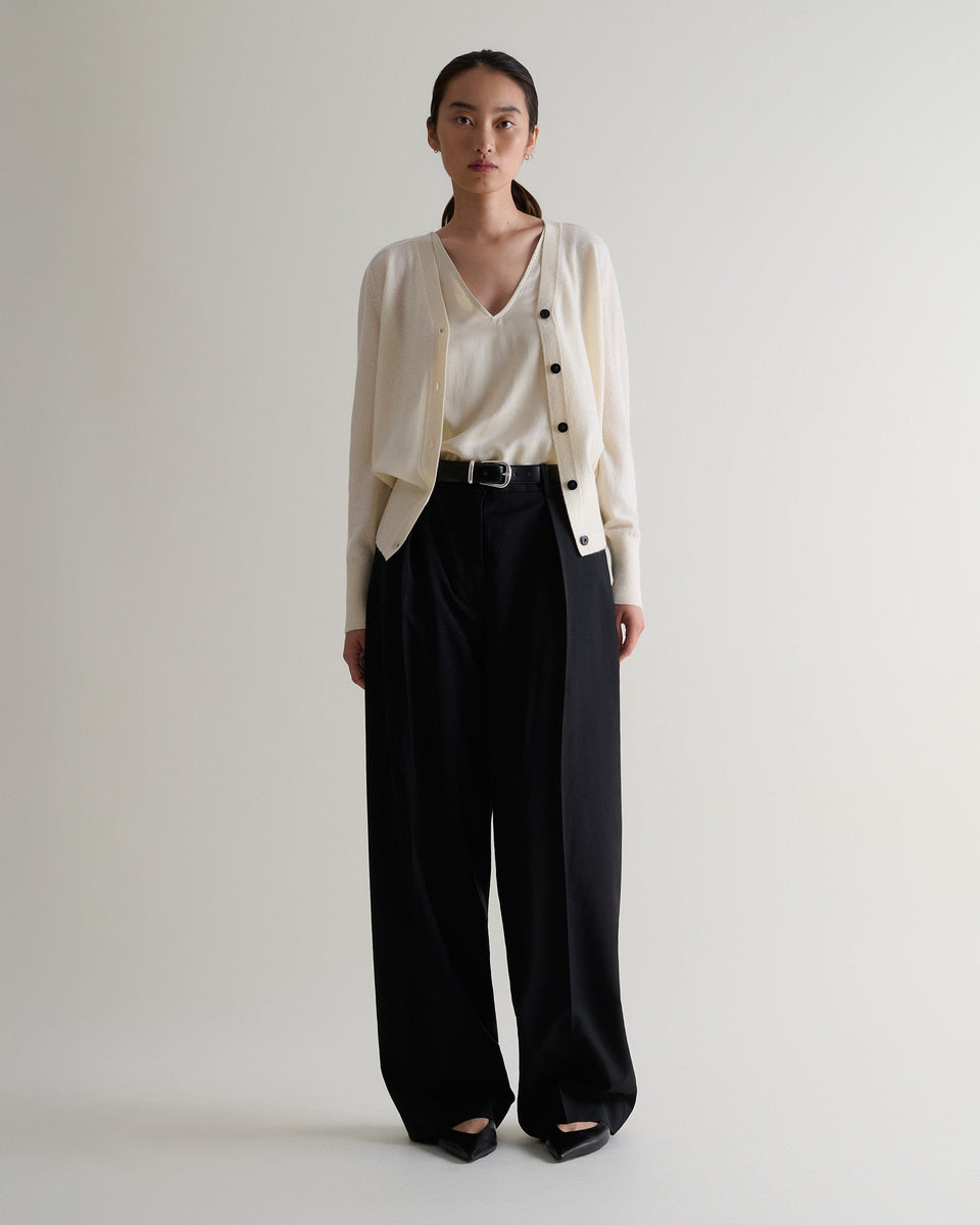 Image 1 of 3 showing woman wearing Rise & Fall's buttermilk fine cashmere blouson cardigan with matching top and black wide leg trousers.