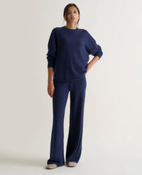 Image 1 of 3 showing woman wearing Rise & Fall's navy fine cashmere wide-leg trousers with matching cashmere sweatshirt.