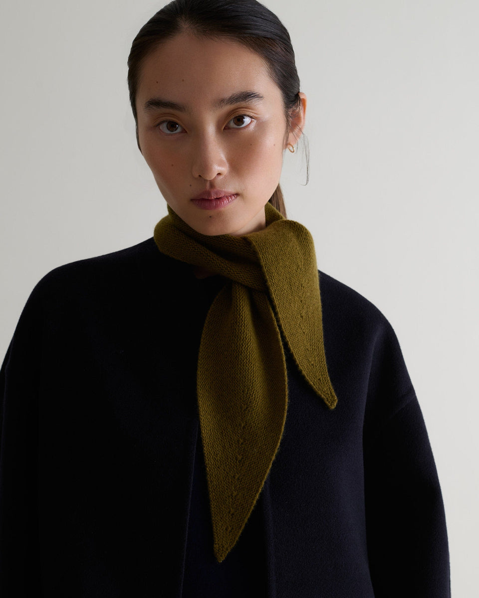 Image 1 of 3 showing woman wearing Rise & Fall's olive cashmere ribbed micro bandanawith black jacket.