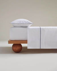 Image 1 of 4 showing Rise & Fall's Crisp & Cool organic cotton percale flat sheet in white navy piping.