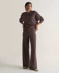 Image 1 of 4 showing woman wearing Rise & Fall's chocolate brown fine cashmere wide-leg trousers with matching cashmere sweatshirt.
