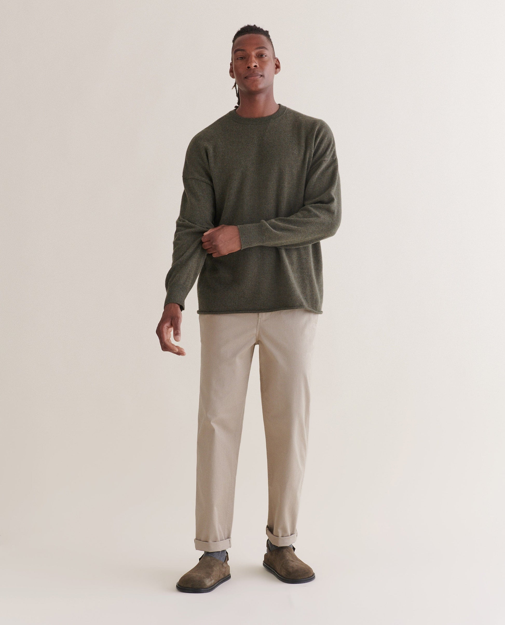 Image 1 of 5 showing man wearing Rise & Fall's finest cashmere mid-weight crew neck jumper in forest green with cream trousers.