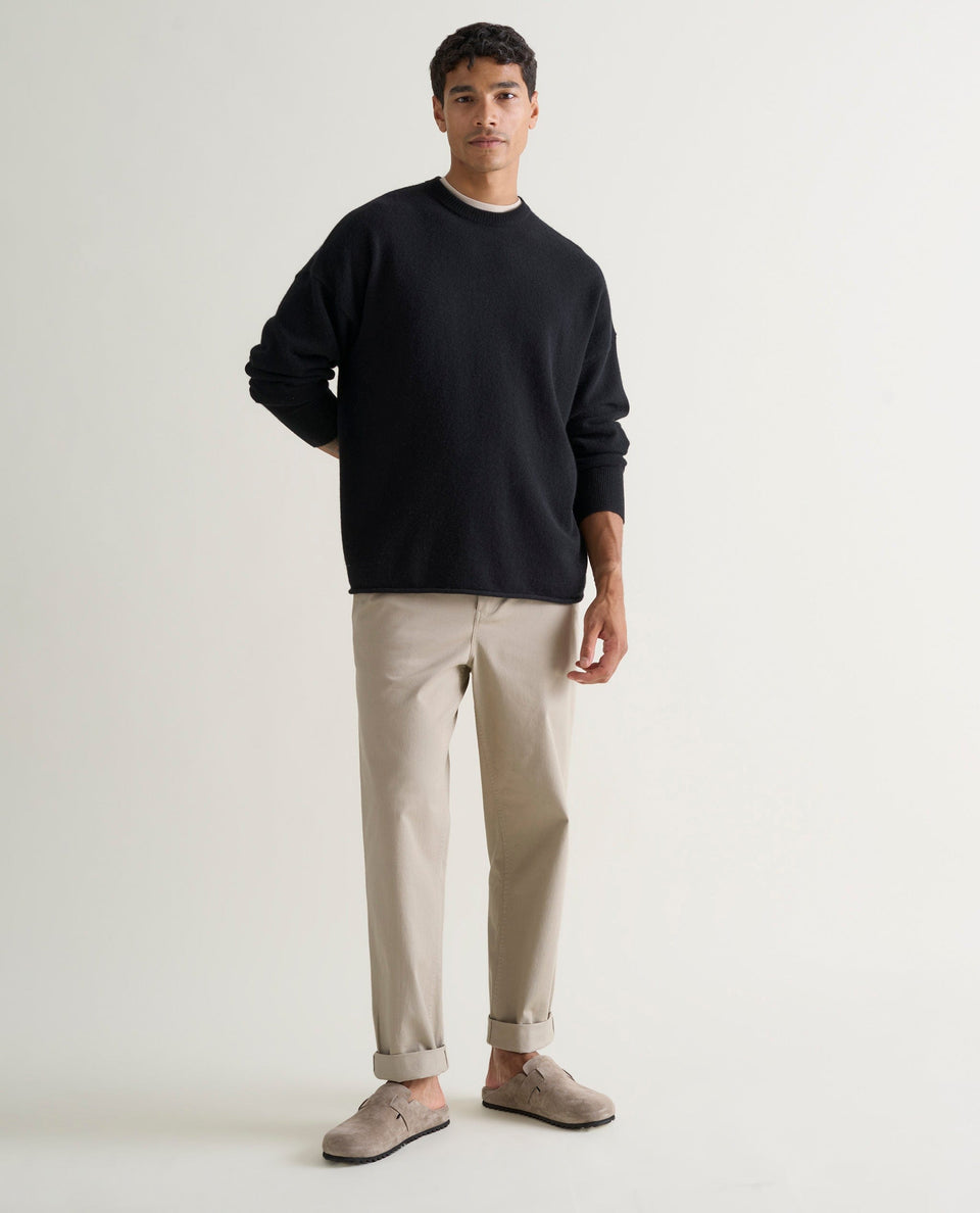 Image 1 of 5 showing man wearing Rise & Fall's black finest cashmere sweatshirt with stone-coloured trousers and suede shoes.