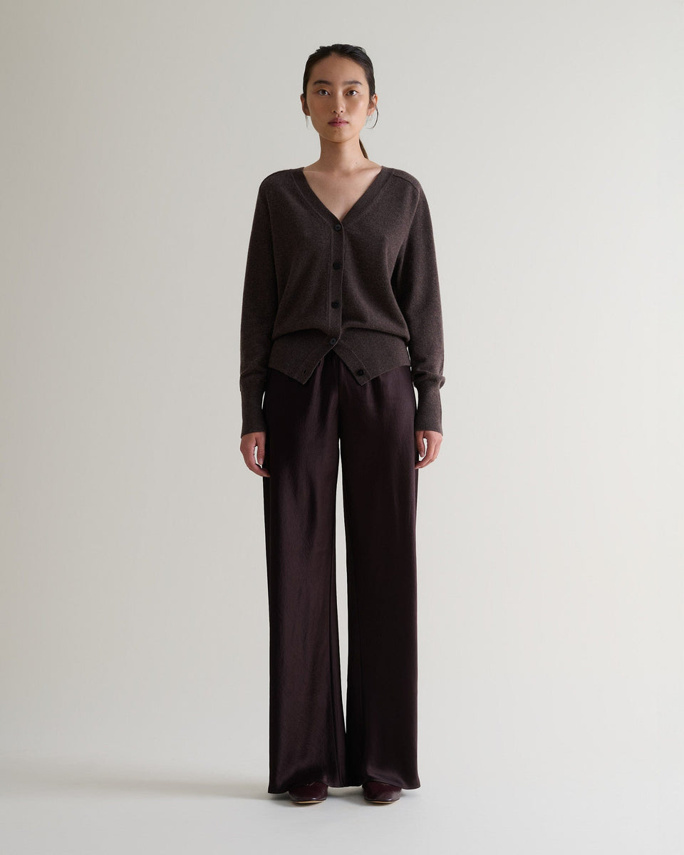 Image 1 of 5 showing woman wearing Rise & Fall's chocolate brown fine cashmere v-neck cardigan with brown silk trousers.