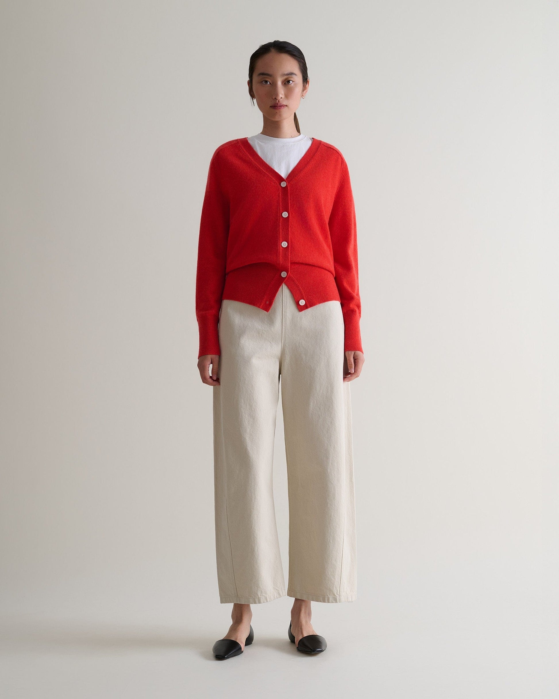 Image 1 of 5 showing Rise & Fall's poppy red fine cashmere blouson cardigan with white T-shirt and cream trousers.