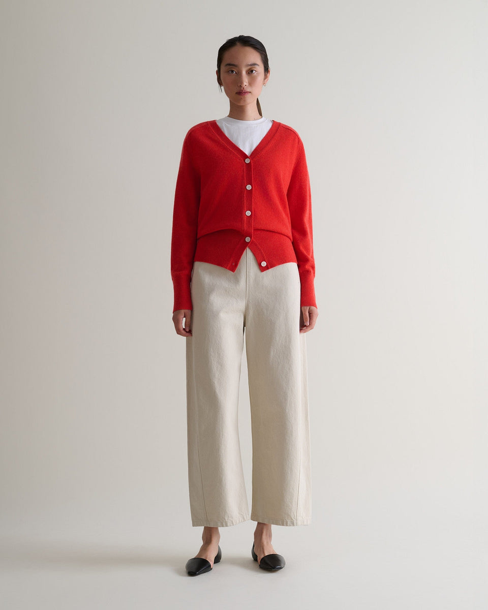 Image 1 of 5 showing Rise & Fall's poppy red fine cashmere blouson cardigan with white T-shirt and cream trousers.
