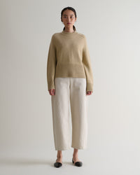 Image 1 of 5 showing woman wearing Rise & Fall twine cashmere merino saddle sleeve crew neck jumper with cream barrel jeans.