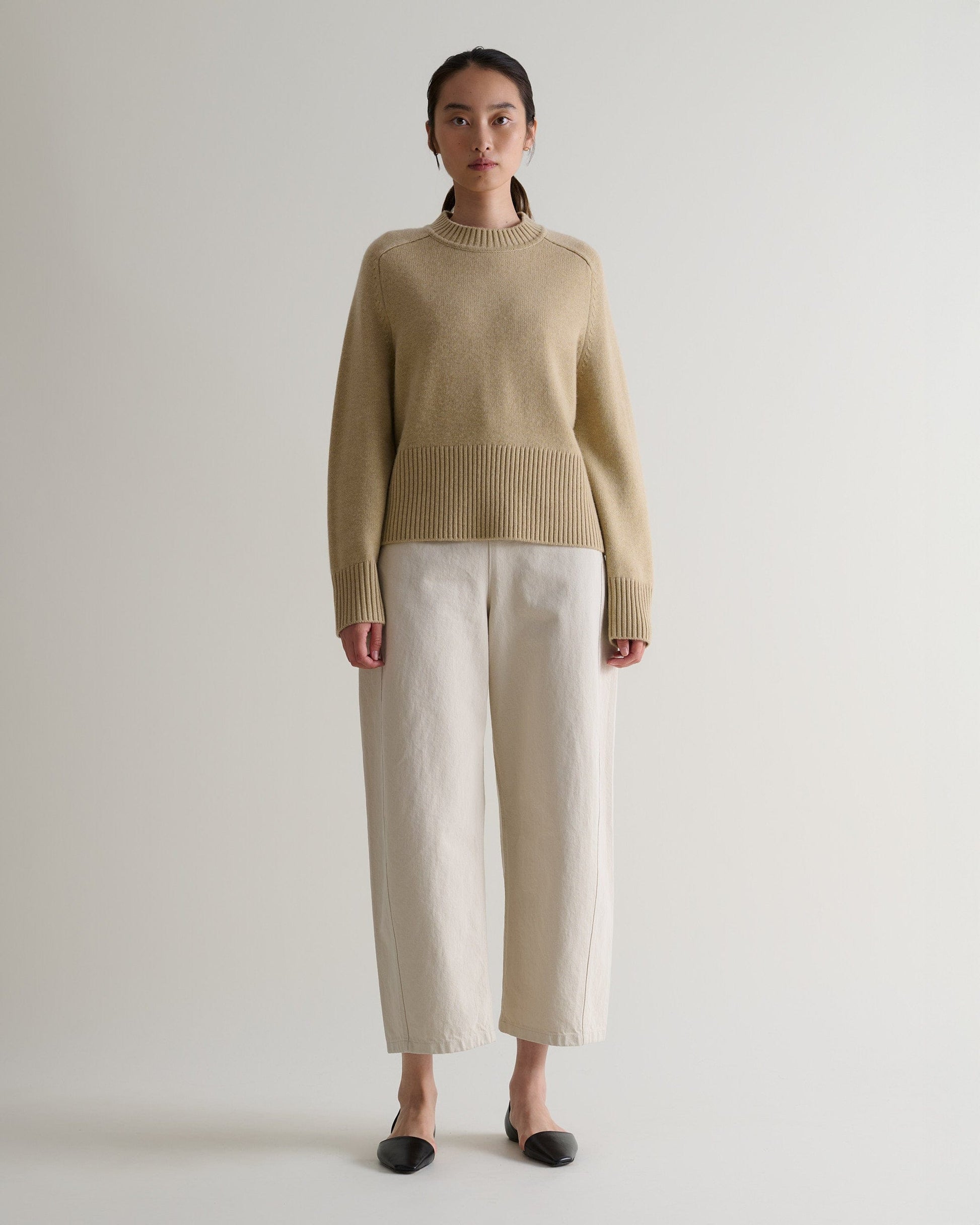 Image 1 of 5 showing woman wearing Rise & Fall twine cashmere merino saddle sleeve crew neck jumper with cream barrel jeans.