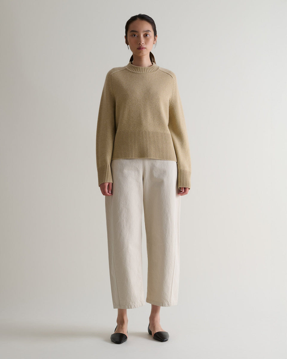 Image 1 of 5 showing woman wearing Rise & Fall twine cashmere merino saddle sleeve crew neck jumper with cream barrel jeans.