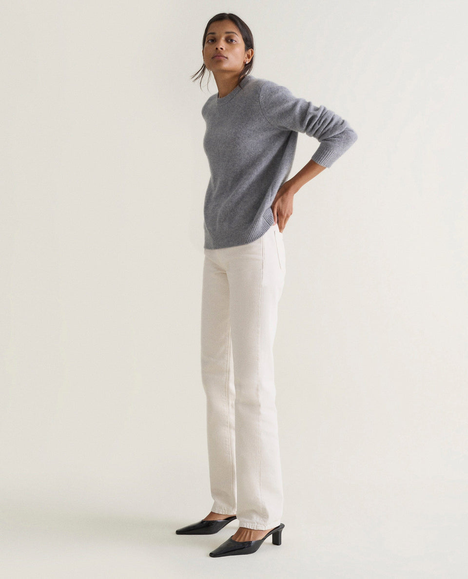 Image 1 of 5 showing woman wearing Rise & Fall's grey mid-weight cashmere crew neck jumper with white jeans.