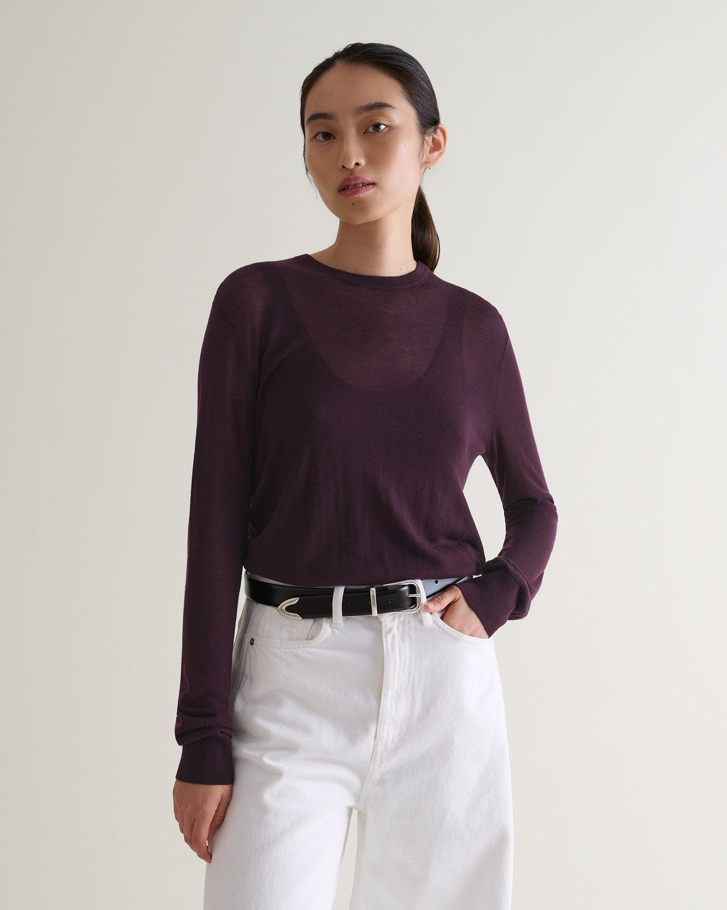 Image 1 of 5 showing a woman wearing Rise & Fall's oxblood tencel™ cashmere double layered crew neck jumper with white jeans and black leather belt. 