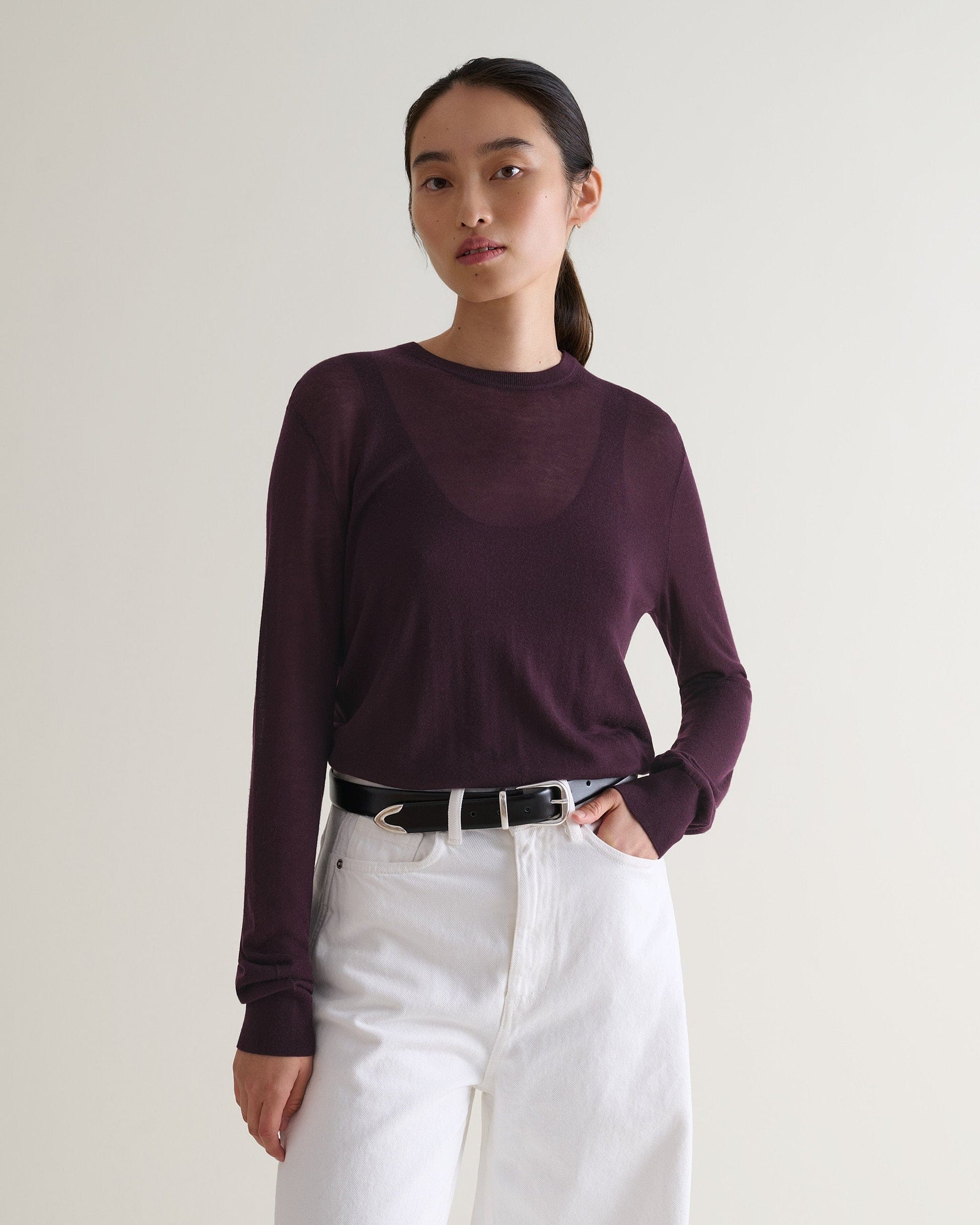 Image 1 of 5 showing a woman wearing Rise & Fall's oxblood tencel™ cashmere double layered crew neck jumper with white jeans and black leather belt. 