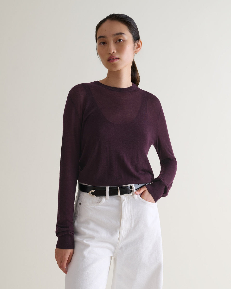 Image 1 of 5 showing a woman wearing Rise & Fall's oxblood tencel™ cashmere double layered crew neck jumper with white jeans and black leather belt. 