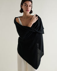 Image 1 of 5 showing woman wrapping Rise & Fall's black oversized cashmere scarf around shoulders. 