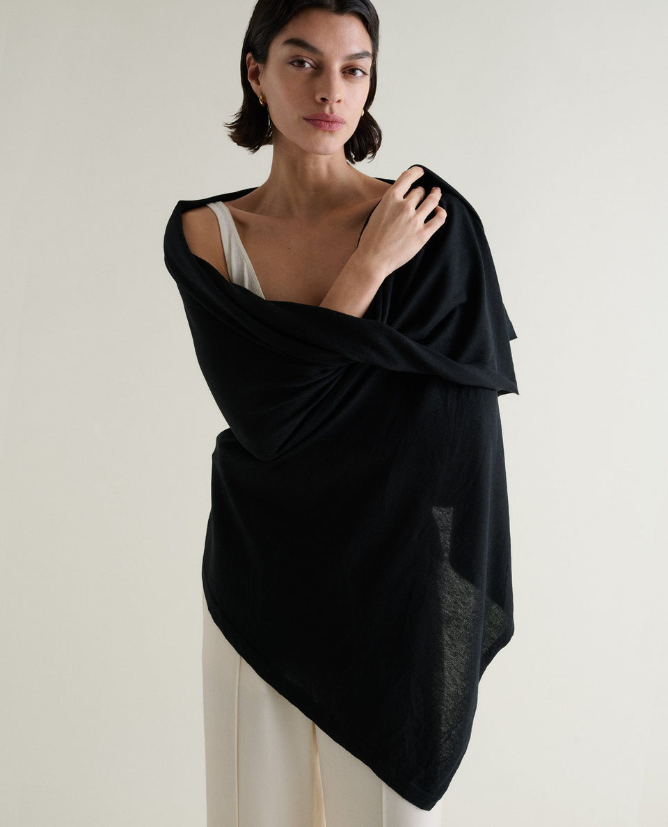 Image 1 of 5 showing woman wrapping Rise & Fall's black oversized cashmere scarf around shoulders. 