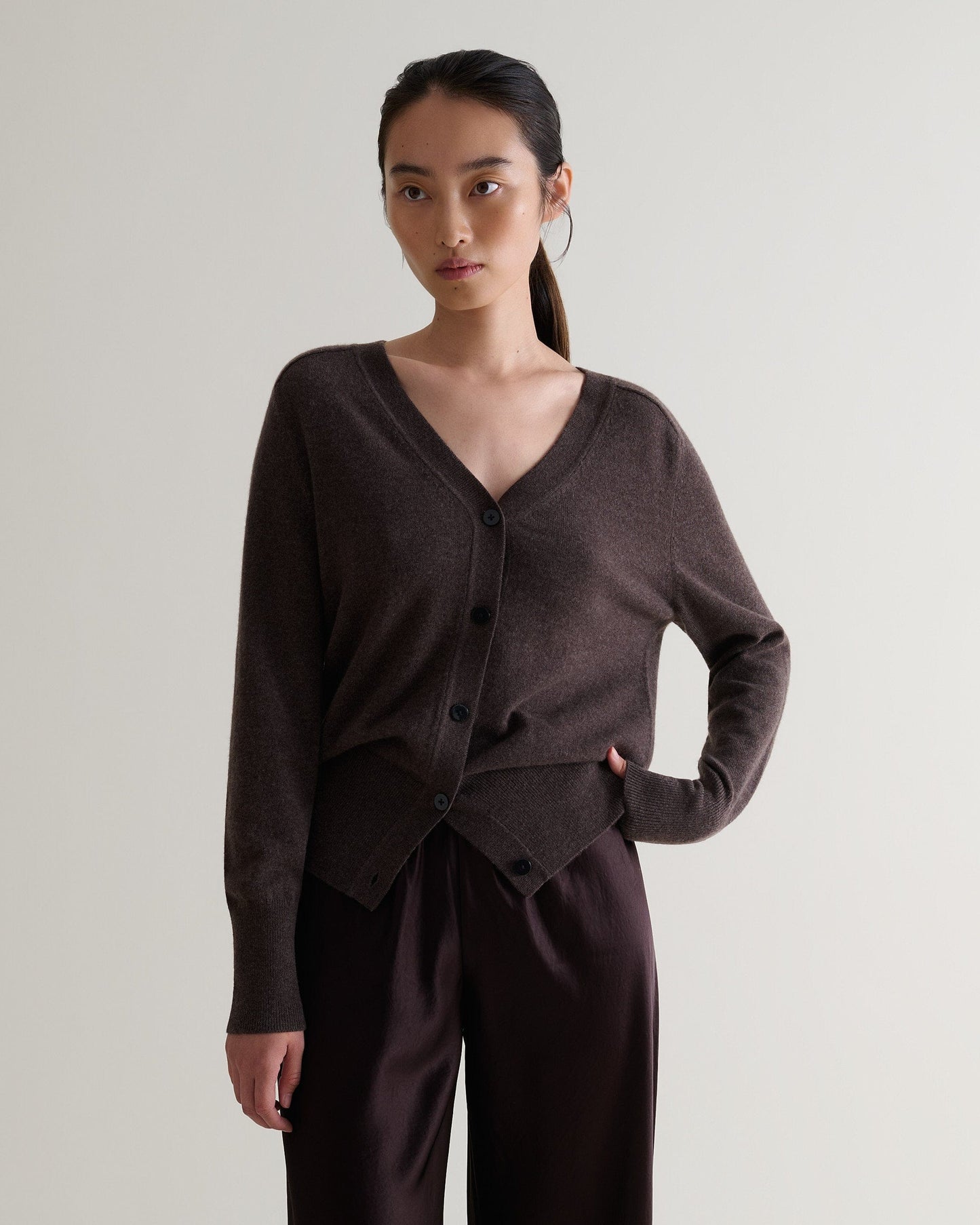 Image 1 of 6 showing woman wearing Rise & Fall's chocolate fine cashmere blouson cardigan with silk brown trousers.