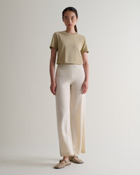 Image 1 of 6 showing woman wearing Rise & Fall's cream fine cashmere wide-leg trousers with beige t-shirt and shoes.